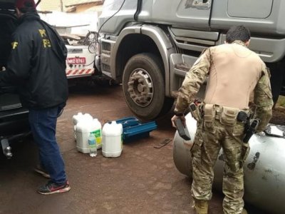 Policiais federais retiram tabletes de maconha do fundo falso em tanque de carreta (Foto: Adilson Domingos)