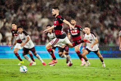 Jogadores disputam a posse da bola sob chuva no gramado. (Foto: Gilvan de Souza/Flamengo)