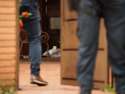 Ao fundo, corpo do auditor fiscal na varanda da casa, coberto (Foto: Renan Kubota).