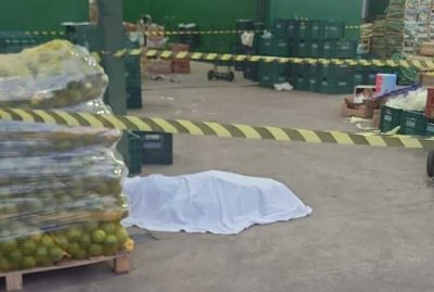 Corpo da v�tima ao lado de palete de laranjas no local onde crime aconteceu (Foto: Direto das Ruas)